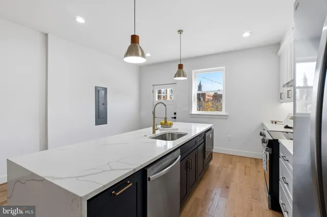 a kitchen with stainless steel appliances granite countertop a sink a stove and a wooden floors