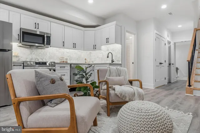 a living room with furniture a flat screen tv and kitchen view