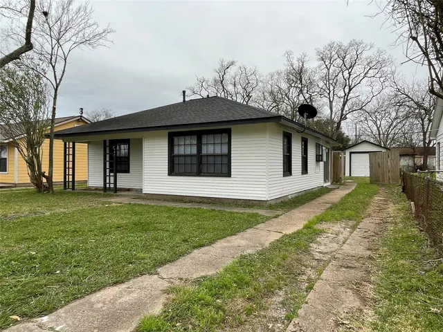 a view of a yard in front of a house with large windows