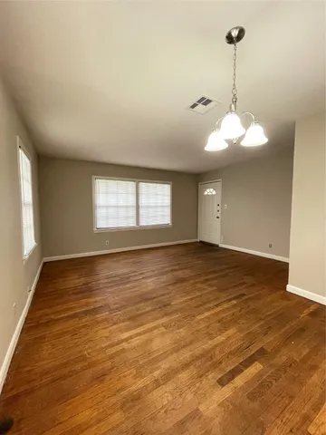 a view of an empty room with window and wooden floor