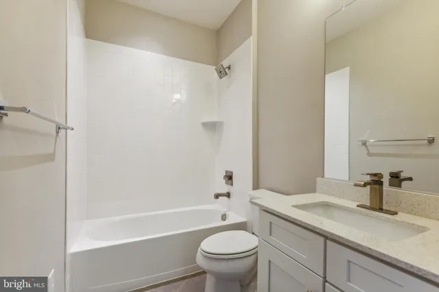 a bathroom with a granite countertop sink a toilet and shower