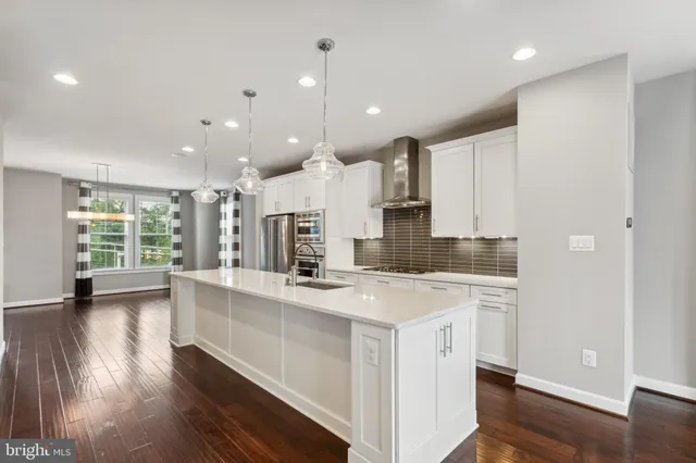 a large kitchen with stainless steel appliances kitchen island a large counter top and a wooden floors