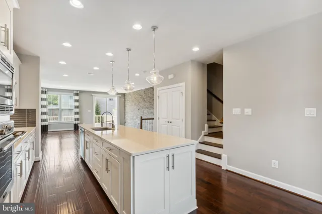 a large white kitchen with a large window a sink and stainless steel appliances