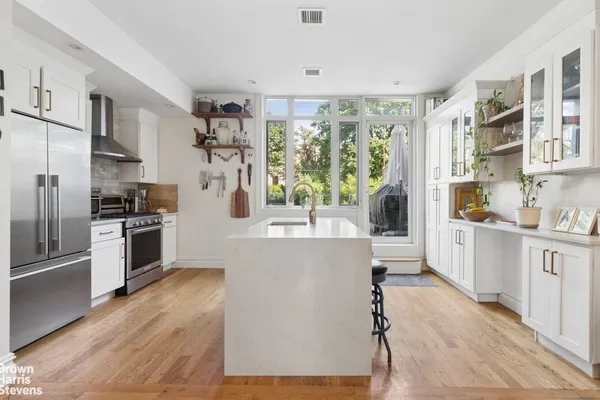 a kitchen with stainless steel appliances a refrigerator a stove a sink and white cabinets with wooden floor