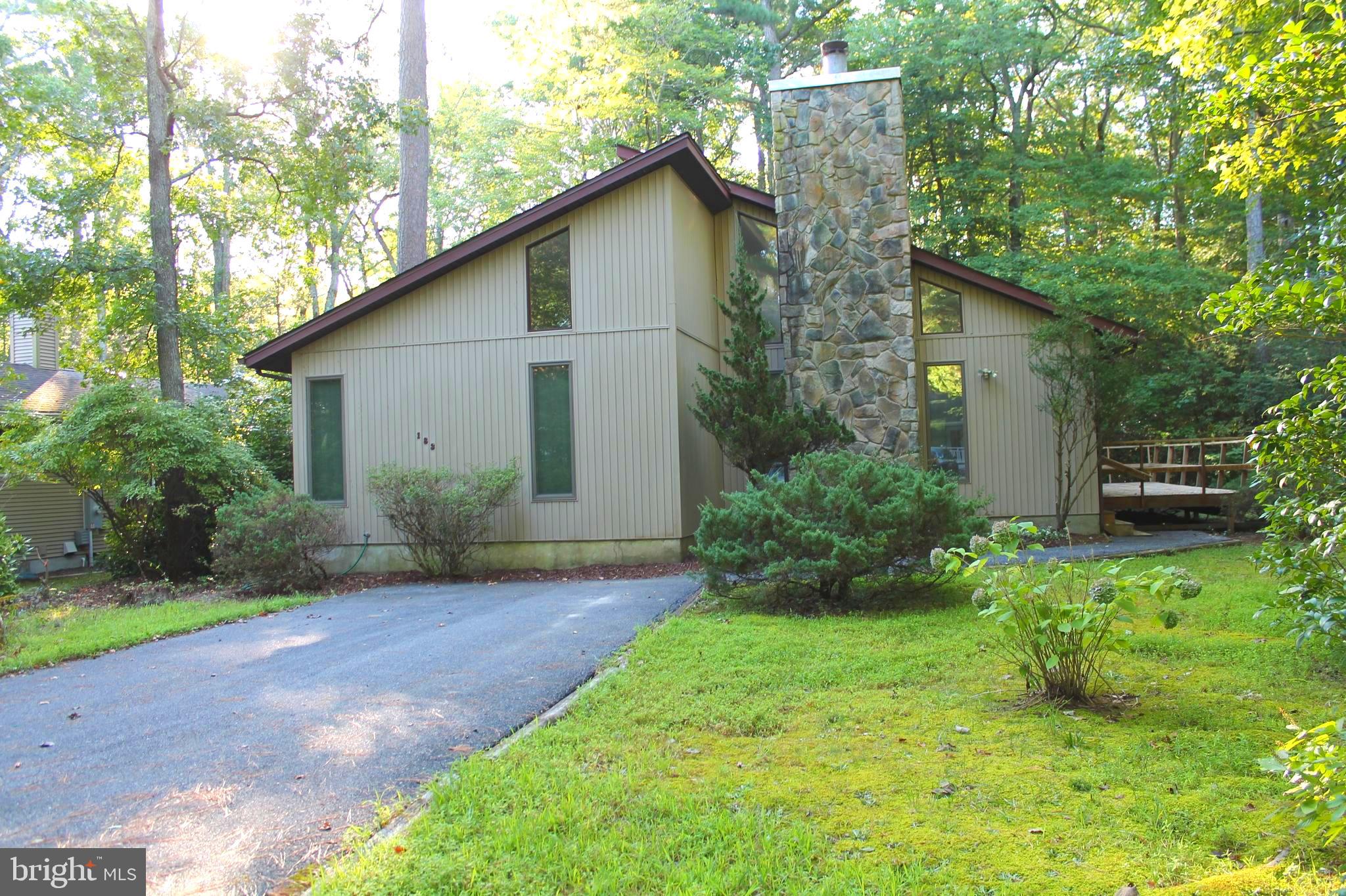183 Sandyhook Road Ocean Pines, MD 21811 - Photo 1 of 15 a yellow house with flower garden in front of it