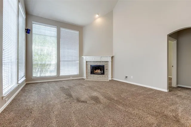 an empty room with windows and fireplace