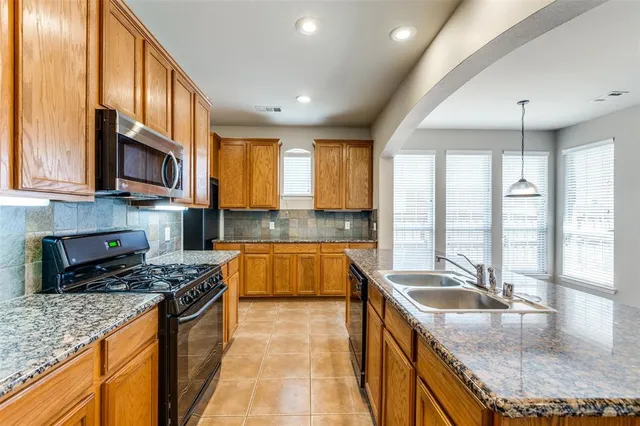 a kitchen with granite countertop a sink a counter top space appliances and cabinets