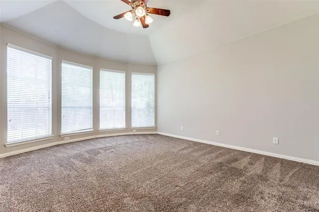 an empty room with a chandelier fan and windows