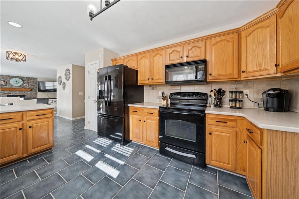 227 Sandworks Road Hunker, PA 15639 - Photo 10 of 41 a kitchen with stainless steel appliances granite countertop a stove top oven a refrigerator and white cabinets with wooden floor