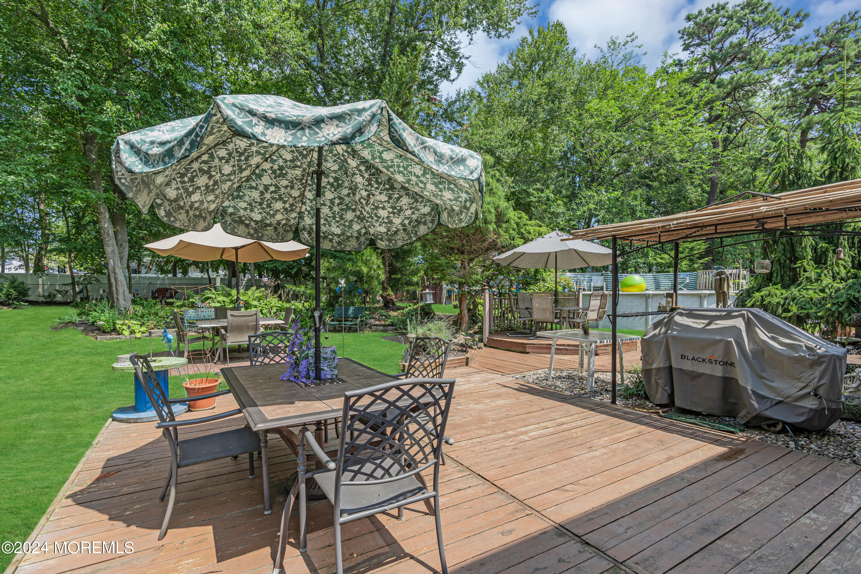 6 Pepperridge Road Howell, NJ 07731 - Photo 31 of 44 a view of a patio with a dining table and chairs under an umbrella with a garden