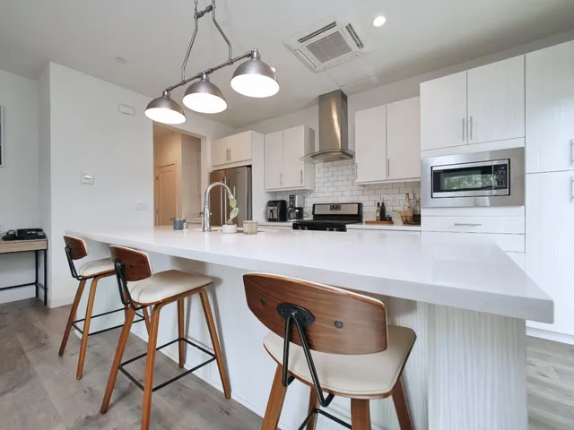 a kitchen with stainless steel appliances a dining table chairs and a refrigerator