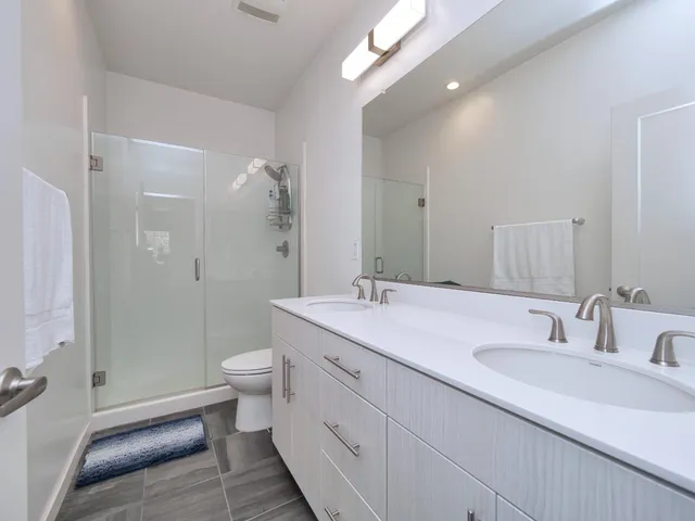 a bathroom with a double vanity sink toilet and shower