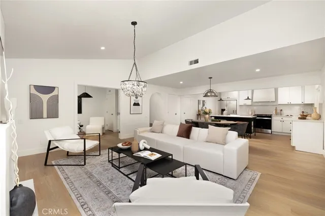 a living room with furniture kitchen view and a chandelier