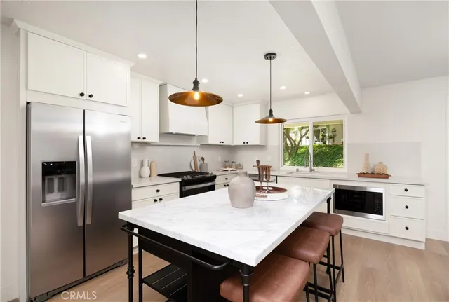 a kitchen with stainless steel appliances a dining table chairs and a refrigerator