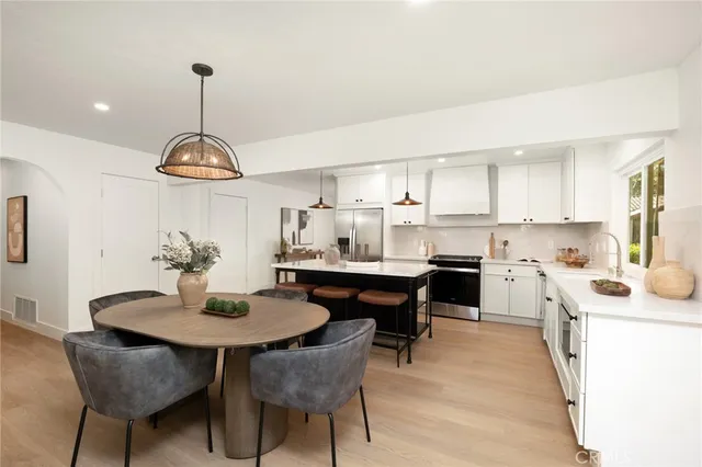 a kitchen with stainless steel appliances kitchen island a table and chairs in it