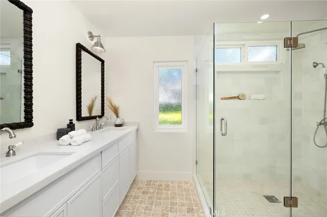 a bathroom with a double vanity sink mirror and shower