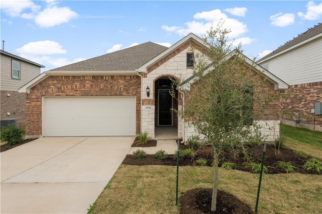 View of front of property with concrete driveway, roof with shingles, stone siding, a garage, and brick siding