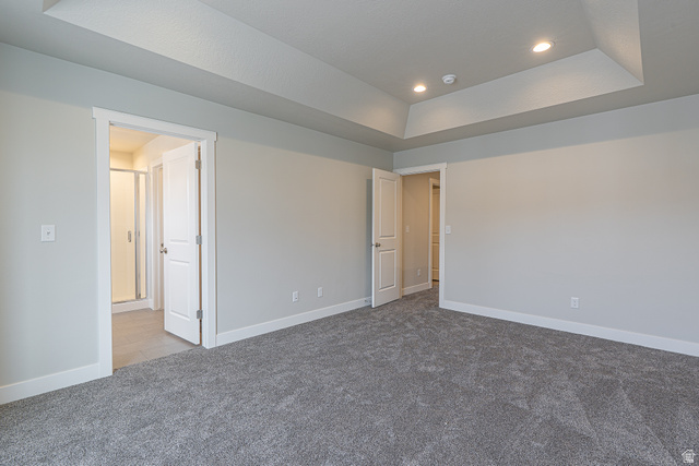 2249 South 1090 West, Unit 76 Nibley, UT 84321 - Photo 16 of 19 Spacious room featuring tray ceiling with recessed lighting, plush grey carpeting, white baseboards, and two solid core doors