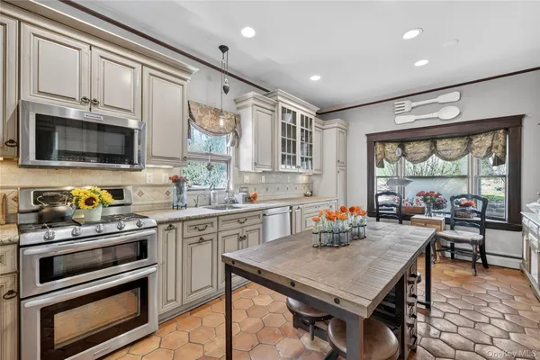 a kitchen with stainless steel appliances granite countertop a stove top oven a sink dishwasher a dining table and chairs with wooden floor