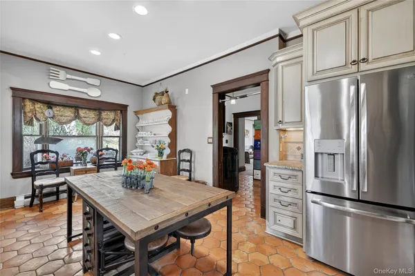 a kitchen with stainless steel appliances granite countertop a refrigerator a stove and a dining table with wooden floor