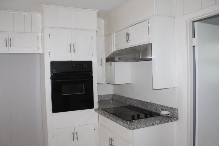 875 Woodrow Street Silsbee, TX 77656 - Photo 16 of 30 a kitchen with white cabinets and black appliances