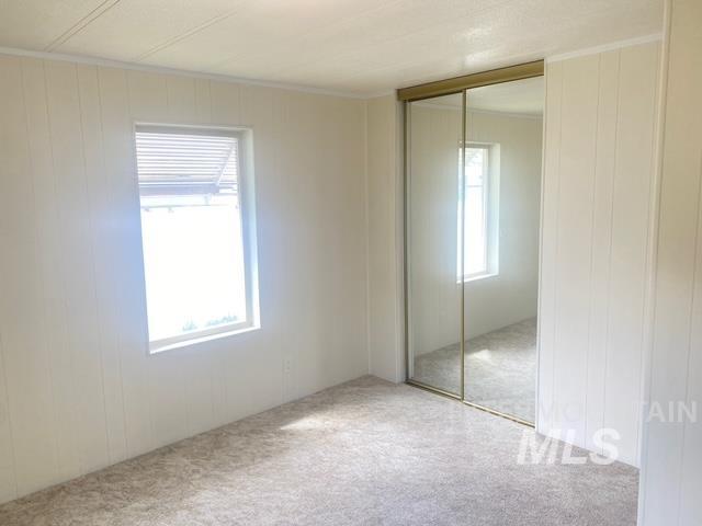 2015 6th Avenue, Unit 131A Clarkston, WA 99403 - Photo 11 of 13 Bedroom featuring a closet, carpet, wood walls, and a decorative wall