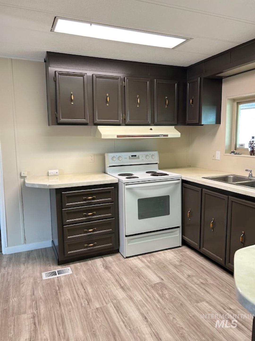 2015 6th Avenue, Unit 131A Clarkston, WA 99403 - Photo 6 of 13 Kitchen featuring white electric range, light wood finished floors, light countertops, and under cabinet range hood