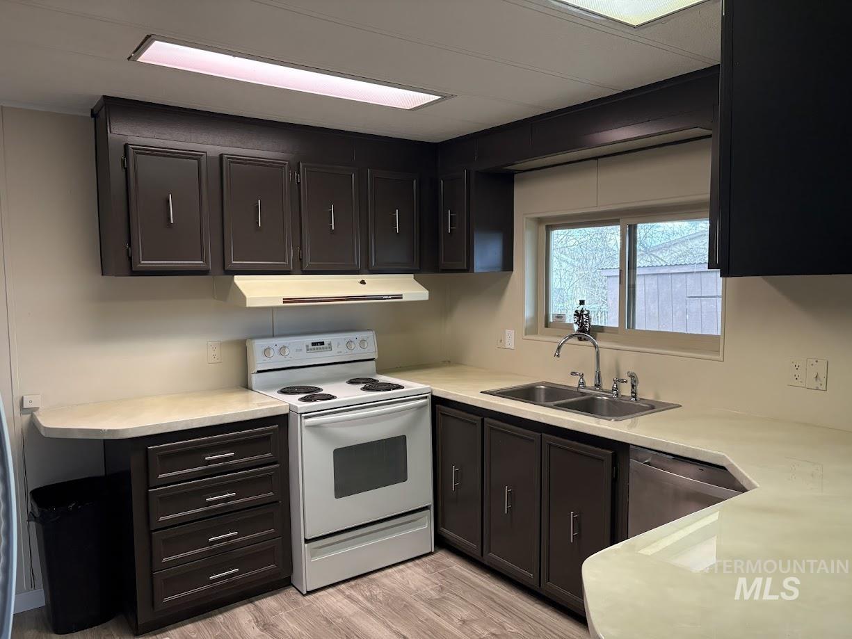 2015 6th Avenue, Unit 131A Clarkston, WA 99403 - Photo 7 of 26 Kitchen with white range with electric stovetop, light countertops, dishwasher, range hood, and light wood-type flooring