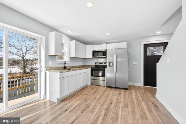 a kitchen with stainless steel appliances granite countertop a refrigerator a sink dishwasher a stove with wooden cabinets and floor