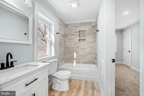 a bathroom with a bathtub shower sink vanity mirror and toilet