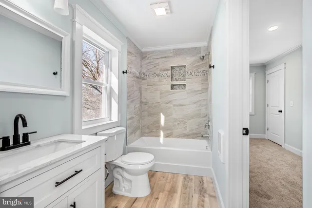 a bathroom with a bathtub shower sink vanity mirror and toilet