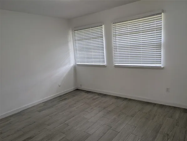 a view of an empty room with wooden floor and closet