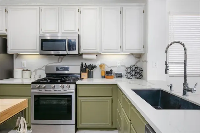 a kitchen with stainless steel appliances granite countertop a stove a sink and a microwave