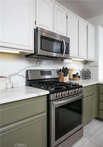 a kitchen with stainless steel appliances granite countertop grey cabinets a stove a sink and dishwasher