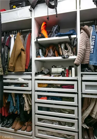 a view of walk in closet with clothes and shoes