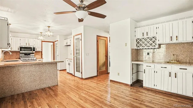 a kitchen with granite countertop a refrigerator a stove a microwave and wooden floor