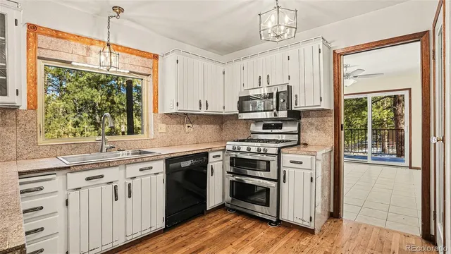 a kitchen with stainless steel appliances white cabinets a stove a sink and a window