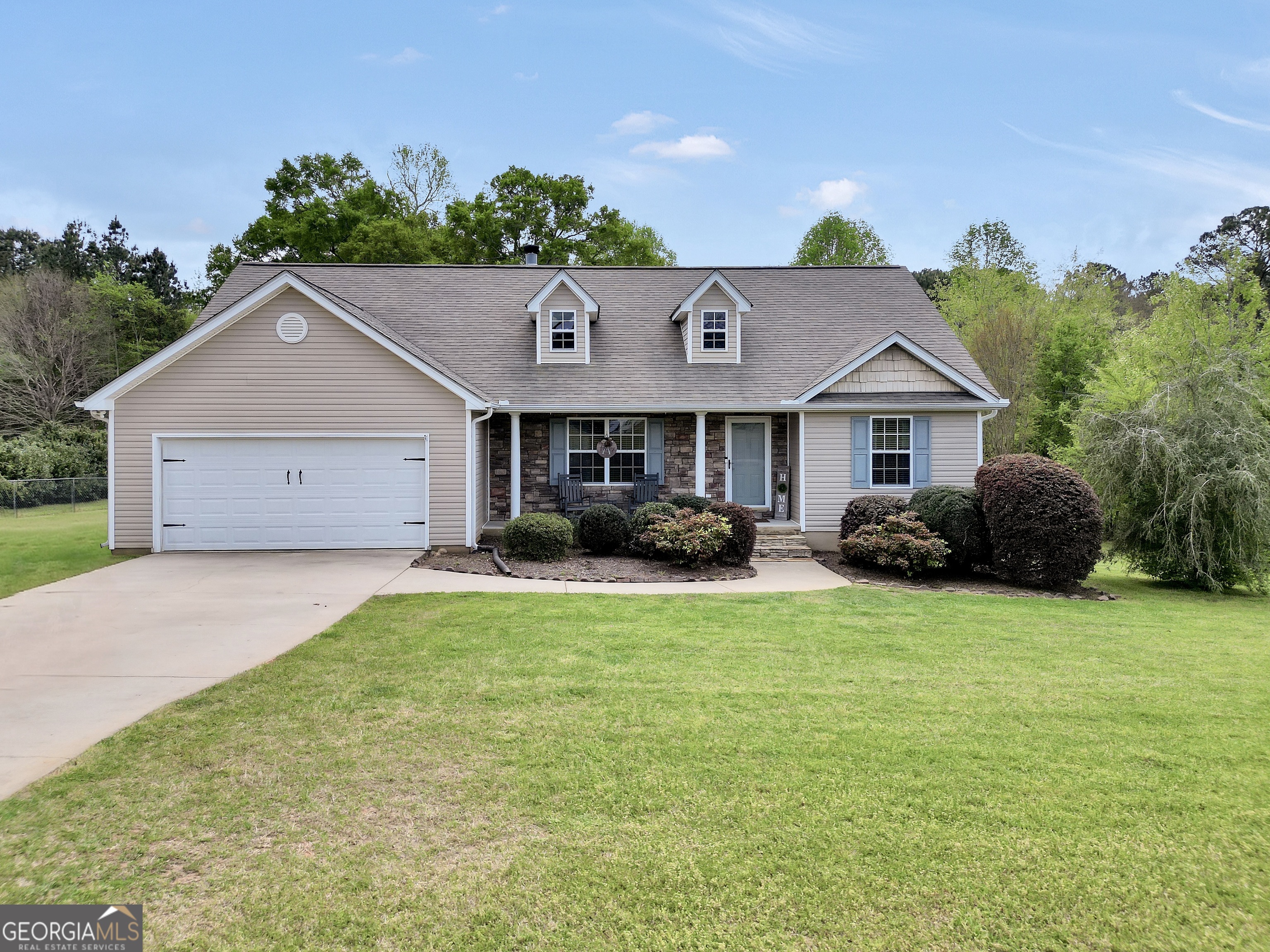 a front view of a house with a garden and trees