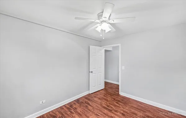 an empty room with wooden floor and fan