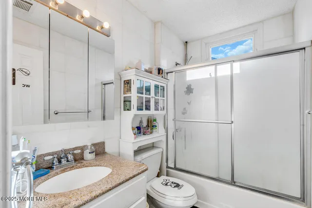 a bathroom with a granite countertop sink toilet and shower