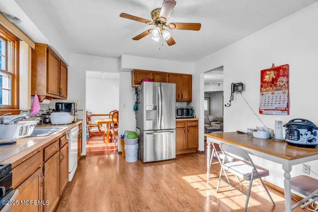 a kitchen with stainless steel appliances granite countertop a refrigerator a stove a sink dishwasher and a dining table with wooden floor