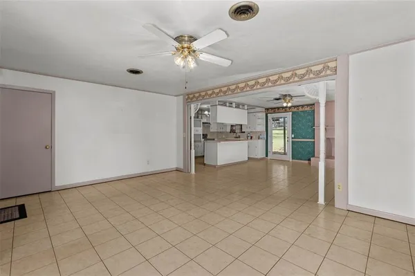 an empty room with chandelier fan and windows