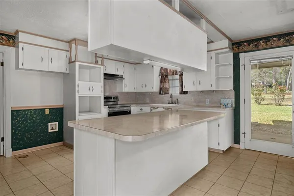 a large kitchen with stainless steel appliances granite countertop a sink and a stove next to a window