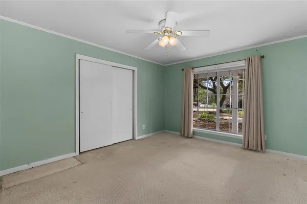 an empty room with chandelier fan and windows