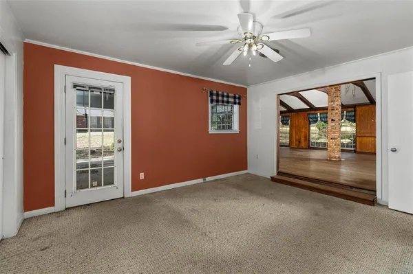 an empty room with chandelier fan and windows