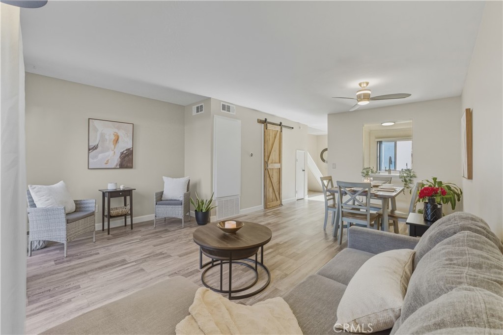 a living room with furniture and a dining table with wooden floor