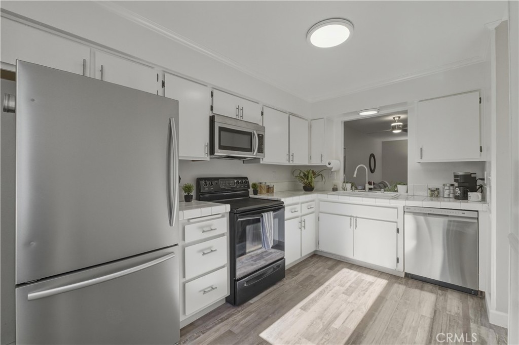 a kitchen with cabinets stainless steel appliances and wooden floor