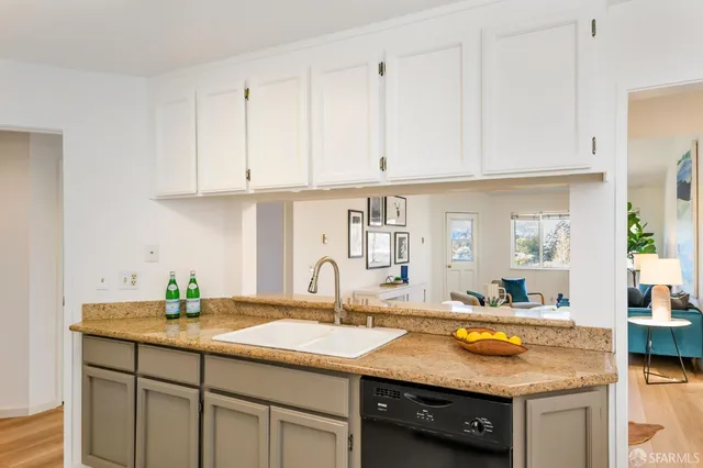 a kitchen with granite countertop a sink and white cabinets