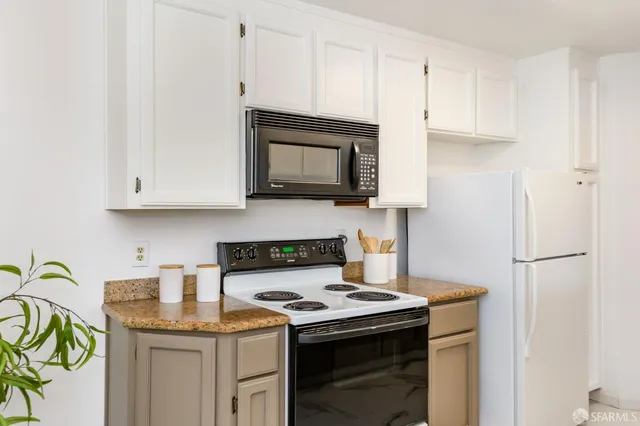 a kitchen with stainless steel appliances granite countertop a stove a microwave and a white cabinets