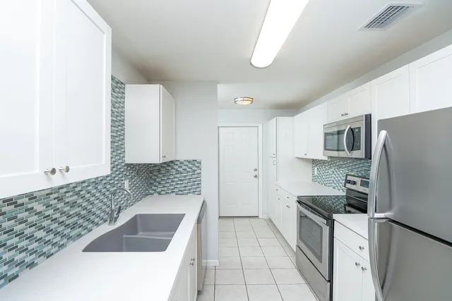 a kitchen with stainless steel appliances kitchen island granite countertop a refrigerator and a stove top oven